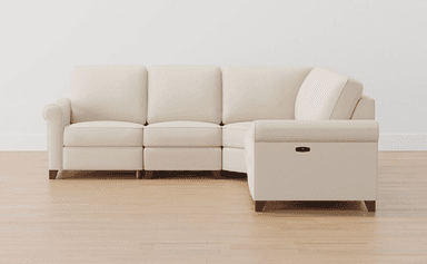 A contemporary L-shaped sectional sofa upholstered in light cream fabric, featuring rolled armrests and multiple seat and back cushions. It is composed of several modules, including an L-corner piece and end sections that have integrated reclining functionality, indicated by a black lever on the armrest. The sofa is supported by short, tapered dark wood legs. — 3D model