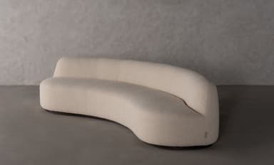 A contemporary curved sofa with a textured upholstery and a flowing, organic shape. The sofa features a single continuous seat and backrest, with no visible arms. The silhouette is sleek and modern, designed to fit within a variety of interior design schemes. — 3D model