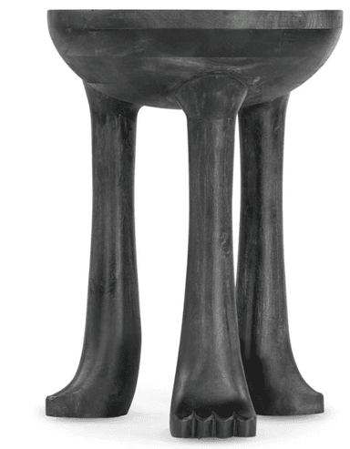 A dark, possibly ebonized, wooden pedestal table featuring a rounded, shallow bowl-like top. The table is supported by three robust, sculpted legs that splay outwards slightly and terminate in stylized foot-like carvings, complete with distinct toe details. The entire piece exhibits a hand-carved, organic aesthetic. — 3D model