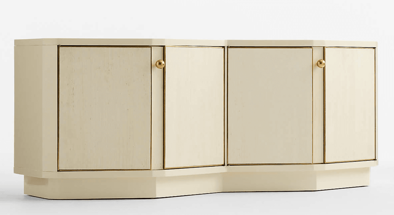 A long, low sideboard cabinet featuring a cream-colored lacquered finish and brass hardware. The facade is subtly segmented with four cabinet doors, each framed by brass trim. The cabinet sits on a recessed plinth base that follows the slight inward curve of the segmented front, giving it a distinctive postmodern appearance. — 3D model