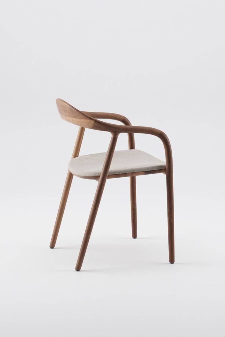 A modern dining armchair featuring a walnut wood frame with a curved backrest, integrated armrests, and a light beige upholstered seat. — 3D model