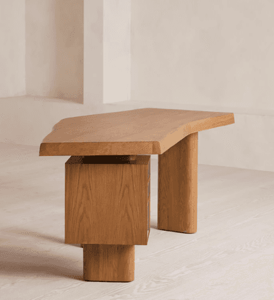 A contemporary desk featuring an irregularly shaped wooden tabletop supported by cylindrical legs and an integrated three-drawer pedestal. The main structure appears to be solid light-toned wood, possibly oak, while the drawer fronts are made from a contrasting darker burl wood veneer, adding a distinctive visual element. The design is minimalist and sculptural. — 3D model