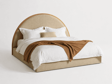 A contemporary bed featuring a distinctive arched headboard constructed with a natural wood frame and a woven cane or rattan insert. The bed base is upholstered in a neutral beige fabric, complementing the natural textures of the headboard. It is shown dressed with crisp white bedding and a warm brown throw blanket. — 3D model