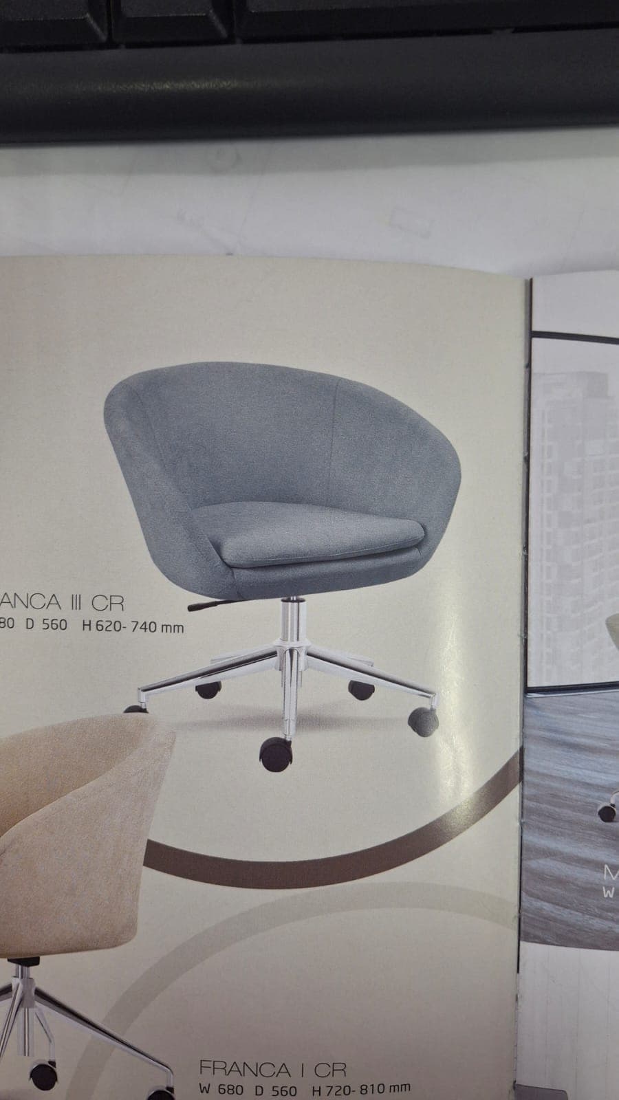A modern upholstered swivel chair designed for desk or office use. It features a rounded bucket-style seat and back, integrated armrests, and a padded seat cushion, all covered in a textured gray fabric. The chair sits on a polished metal five-star base equipped with black rolling casters and a visible lever for height adjustment. — 3D model