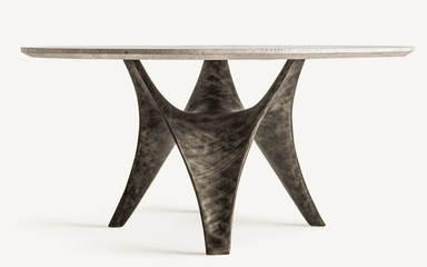 A round coffee table with a light-colored, textured stone or composite top and a unique, sculptural base. The base features multiple curved, organic-shaped legs that twist and converge towards the center, creating a dynamic and artistic silhouette. The finish on the base appears metallic with variations in tone, suggesting a patinated or distressed metal. — 3D model