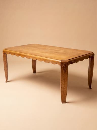 A rectangular dining table crafted from oak wood, featuring a distinctive scalloped apron and decorative carved embellishments on its corners. The table stands on four tapered legs with a subtle curve, reflecting an Art Deco or transitional design. — 3D model