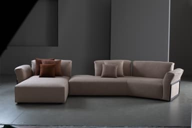 A contemporary modular sectional sofa upholstered in a light beige textured fabric, featuring a left-hand chaise lounge and a right-hand armrest with a distinctive dark framed detail. It is adorned with several brown and beige throw pillows. — 3D model