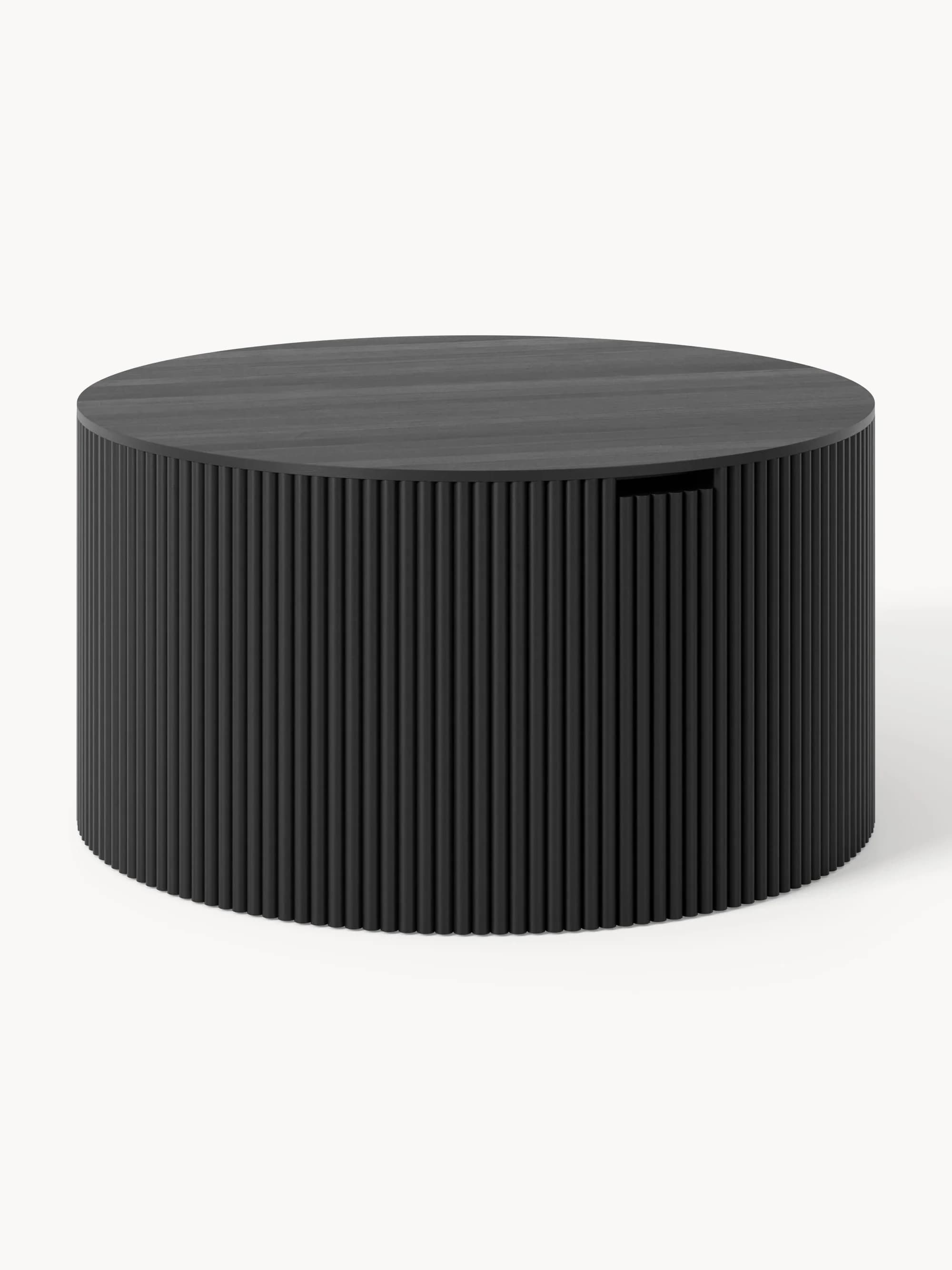 A contemporary, dark-finished coffee table featuring a solid cylindrical form. The exterior is composed of vertical fluted or reeded panels, creating a textured surface. The top surface is smooth, with a visible wood grain pattern, and there's a subtle cut-out or handle on the side, indicating integrated storage or a rotational element. — 3D model