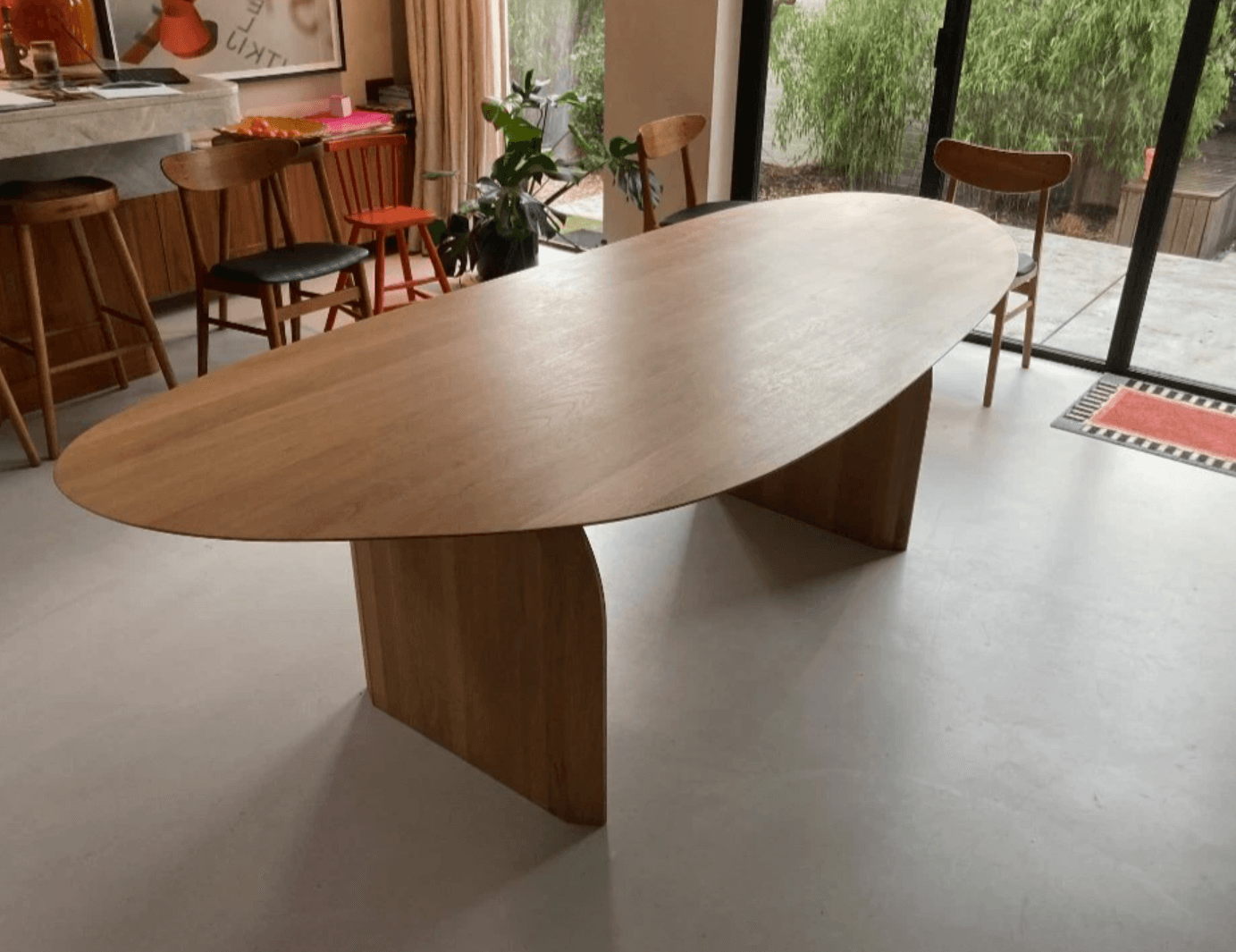 An oval coffee table with a light wood finish and two angled pedestal bases. The table has a minimalist and modern design. — 3D model