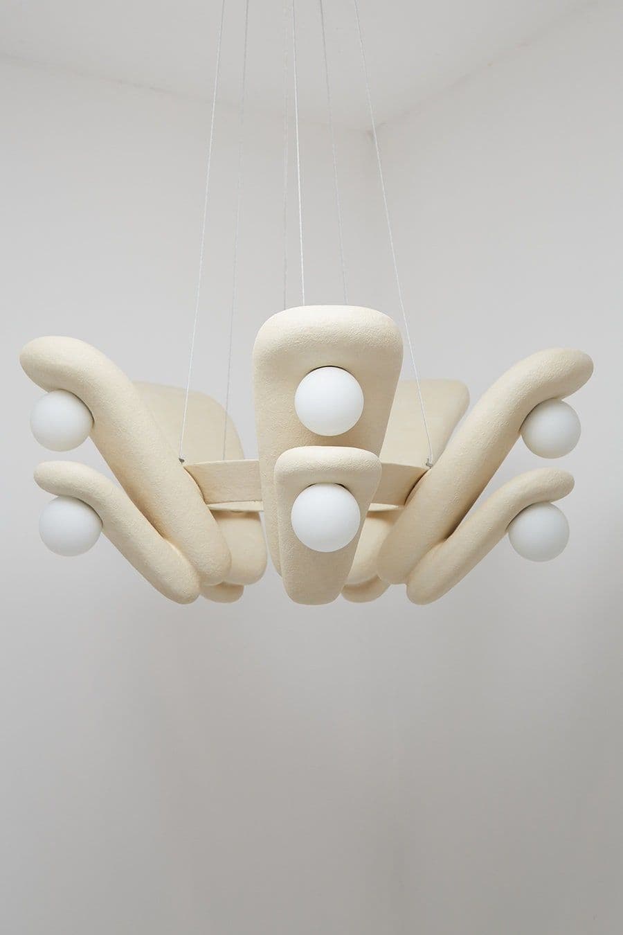 A modern chandelier with an organic, sculptural design. It features a central cluster of bulbous forms from which curved arms extend outwards, each terminating in a spherical light source. The structure appears to be suspended by thin wires. — 3D model