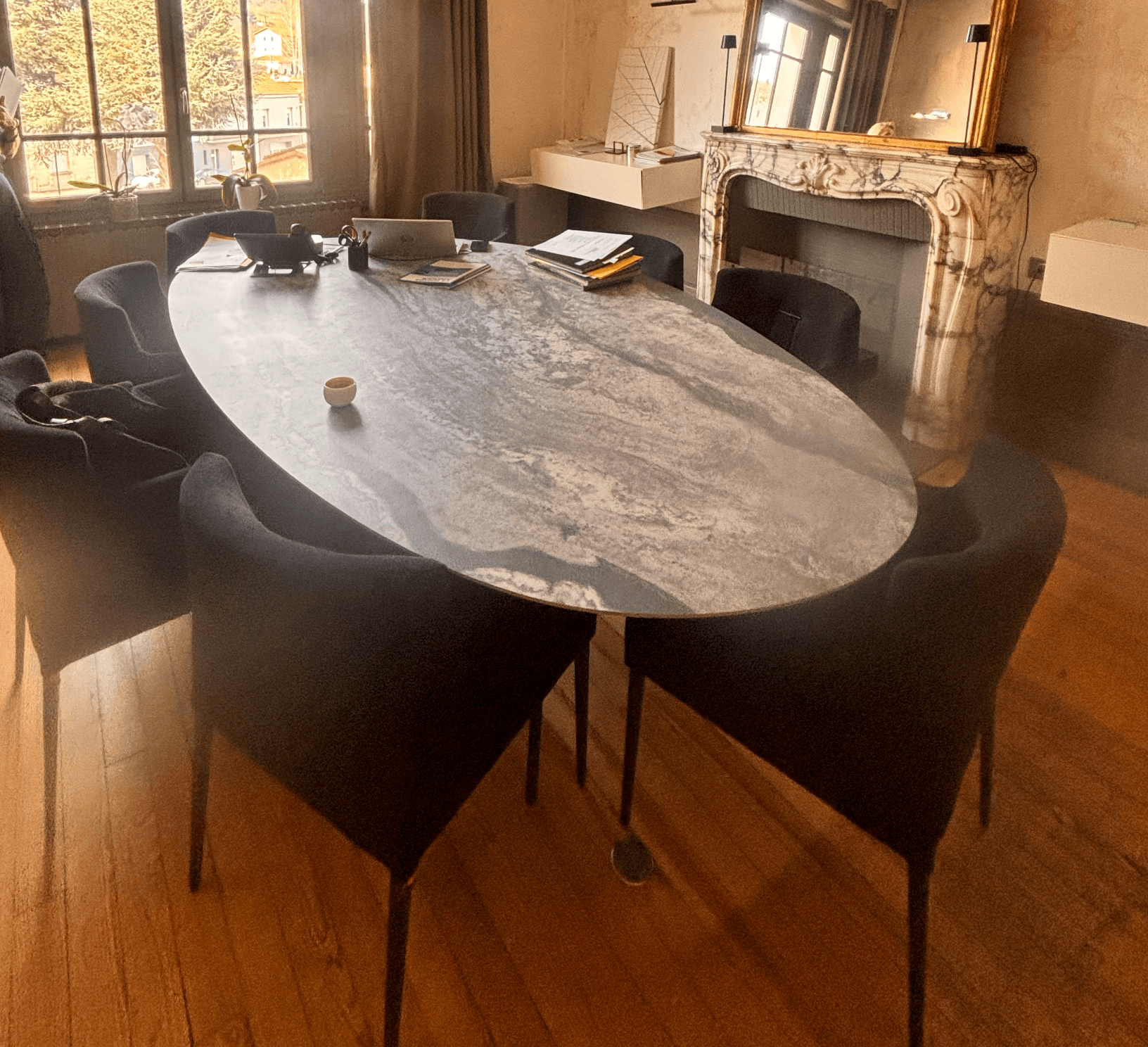 An oval-shaped coffee table featuring a grey marble-effect top with naturalistic veining, supported by four slender, tapered black metal legs. — 3D model