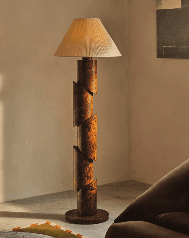 A modernist floor lamp featuring a segmented, cylindrical column base with a burl wood-like pattern, topped with a conical, pleated fabric shade. The base is composed of several cylindrical sections that appear to be cut diagonally and offset, creating a dynamic, spiraling effect. — 3D model