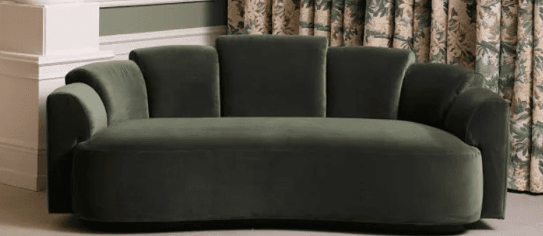 A contemporary curved sofa upholstered in dark green velvet, featuring a distinctive fluted backrest design. — 3D model