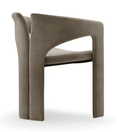 A contemporary armchair featuring a fully upholstered form in a neutral taupe or greige velvet-like fabric. The design incorporates a distinctive U-shaped armrest that flows into the front legs, paired with a separate, slightly curved backrest that extends downwards to form the rear legs. The entire structure is seamless and upholstered, giving it a plush, monolithic appearance. — 3D model