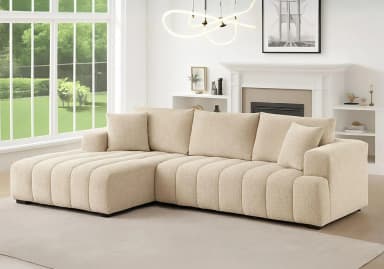 A modern L-shaped sectional sofa with a fixed left-hand chaise, upholstered in a light-colored woven fabric. The base and chaise feature distinctive vertical channel tufting. It includes multiple loose back cushions and accent pillows, supported by discreet black block feet. — 3D model