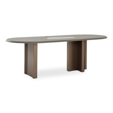 A contemporary oval dining table featuring a light grey wood-grain tabletop with a central lighter-toned, possibly ceramic or stone, inlay. The table is supported by an asymmetrical base design, with one side comprising two rectangular post legs and the other side featuring a solid, fluted, or slatted pedestal base. Both base elements are a uniform taupe-brown color. — 3D model