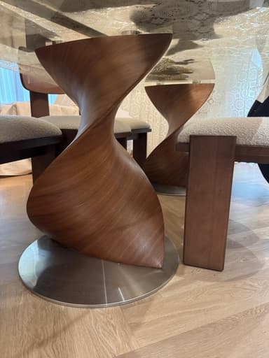 A modern sculptural accent table featuring a unique twisted, hourglass-like form crafted from rich walnut wood veneer, set upon a round, flat metal base. The design emphasizes organic curves and a dynamic silhouette, making it suitable for both functional and decorative purposes. — 3D model