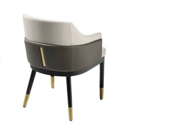 A modern upholstered armchair featuring a curved backrest and integrated armrests, rendered in a two-tone upholstery scheme with a light-colored main body and darker exterior arm panels. It stands on dark wooden tapered legs, which are capped with elegant brass ferrules. — 3D model
