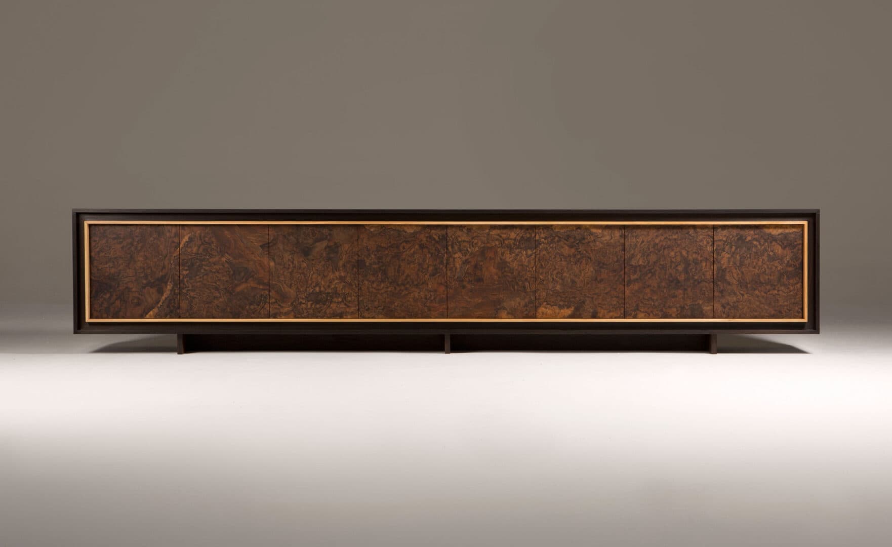 A long, low credenza with a dark frame and a distinctive burl wood veneer on its six cabinet doors. A thin, lighter colored trim surrounds the burl wood panels. — 3D model
