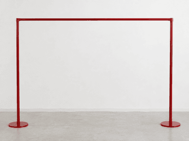 A minimalist, freestanding garment rack made from red-painted metal, featuring two vertical poles with circular bases connected by a single horizontal bar for hanging clothes. — 3D model