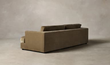 A contemporary sofa with a plush, textured upholstery. It features a low-profile rectangular base, straight arms that curve slightly outwards at the top, and a deep seat cushion. The backrest is divided into two distinct rectangular cushions, providing ample seating space. The overall design is minimalist and modern, with clean lines and a focus on comfort and material. — 3D model