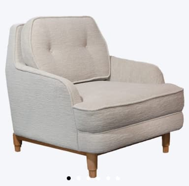 A upholstered armchair with a tufted back cushion. The armchair features a rounded silhouette with padded arms and a fixed seat cushion. It is supported by four tapered wooden legs. — 3D model
