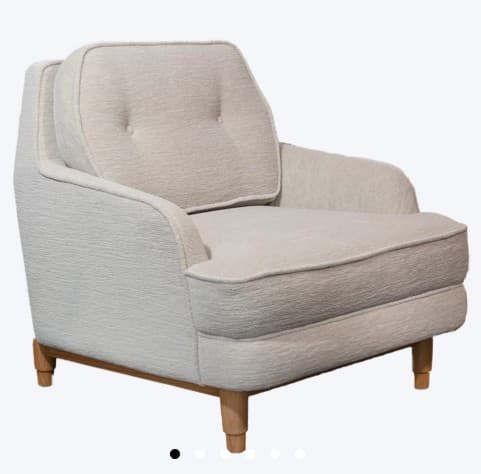 A upholstered armchair with a tufted back cushion. The armchair features a rounded silhouette with padded arms and a fixed seat cushion. It is supported by four tapered wooden legs. — 3D model