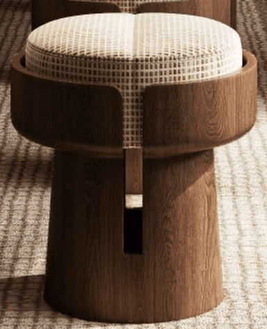 A contemporary stool featuring a cylindrical wooden base with a flared top section. The base has a cut-out detail on one side, revealing an internal wooden element. The seat is round and upholstered with a light-colored fabric featuring a subtle checkered pattern. The overall design is modern and sculptural. — 3D model
