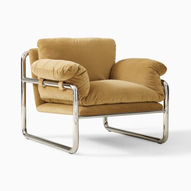 A modern armchair with a tubular chrome-plated steel frame and upholstered cushions. The frame forms a continuous loop supporting the seat, back, and armrests. The cushions appear to be filled with down or similar soft material, covered in a tan-colored fabric. — 3D model