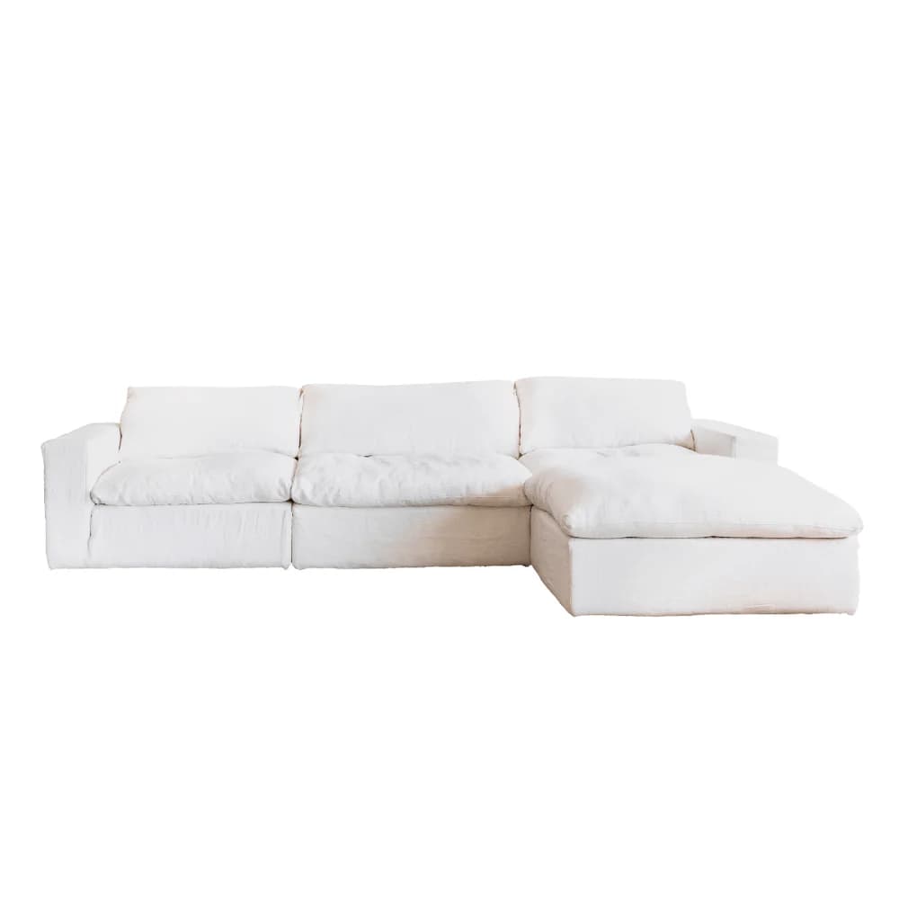 A sectional sofa with a chaise lounge extension, upholstered in white fabric. The sofa features multiple seat cushions and back cushions, with a slightly relaxed, slipcovered appearance. — 3D model