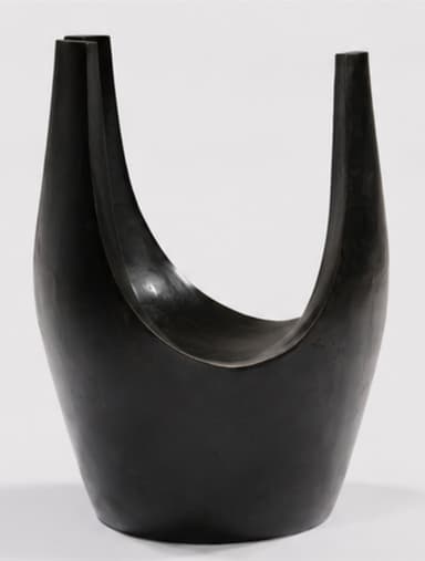 A dark, U-shaped sculptural stool, likely crafted from patinated bronze or ebonized wood. Its form is fluid and organic, with a deep, curved seat integrated into the continuous structure. The material exhibits a smooth, subtly reflective finish. — 3D model