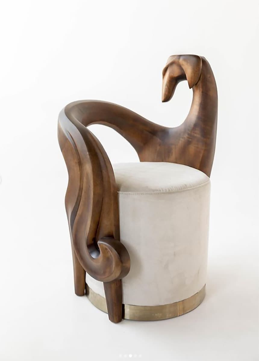 A highly sculptural armchair featuring a dark wood frame with organic, sweeping lines and a distinctive stylized animal head as the backrest. The seat is a plush, cylindrical cushion upholstered in light beige fabric, accented with a brass band at its base. — 3D model