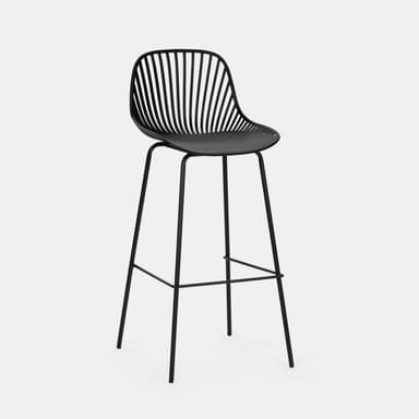 A modern black bar stool with a distinctive design. The seat and backrest are formed by a molded, curved shell with a matte finish, accented by numerous thin, vertical slats that create a semi-transparent effect. The seat itself appears solid and slightly concave for comfort. It is supported by a slender, black metal frame consisting of four legs that are angled outwards for stability, connected by a circular footrest. The overall aesthetic is minimalist and contemporary. — 3D model