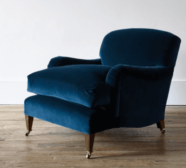 A deep green upholstered armchair with a curved back and rolled arms. It features a loose seat cushion and is supported by four wooden legs, with the front two legs equipped with brass casters. The upholstery appears to be a textured fabric. — 3D model