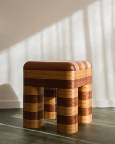 A small, four-legged stool with a striped pattern created by alternating wood tones. The top surface is rounded and the legs are cylindrical with rounded edges. The contrasting wood grain suggests a visually striking design. — 3D model