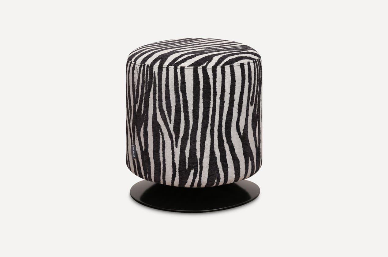 A cylindrical ottoman upholstered in a distinctive black and white zebra print fabric, featuring a flat, circular black base, likely indicating swivel functionality. — 3D model