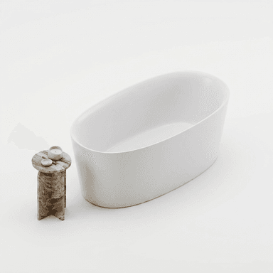 A freestanding, oval-shaped bathtub with a smooth, matte white exterior and interior. The tub has a solid, seamless construction with a gently sloping rim. It is positioned next to a small, circular side table with a multi-colored, veined stone top and a cross-shaped base. Two small white candles and a dish are placed on the side table. — 3D model