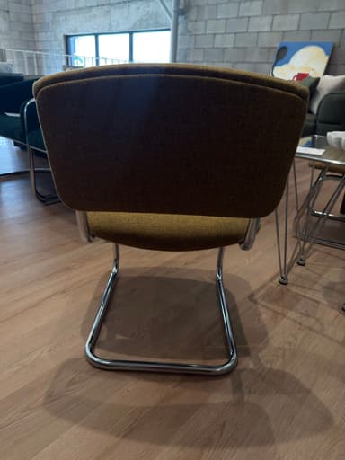 A cantilever dining chair featuring a tubular chrome frame and upholstered seat and backrest in a light beige fabric, with button tufting on the back. — 3D model