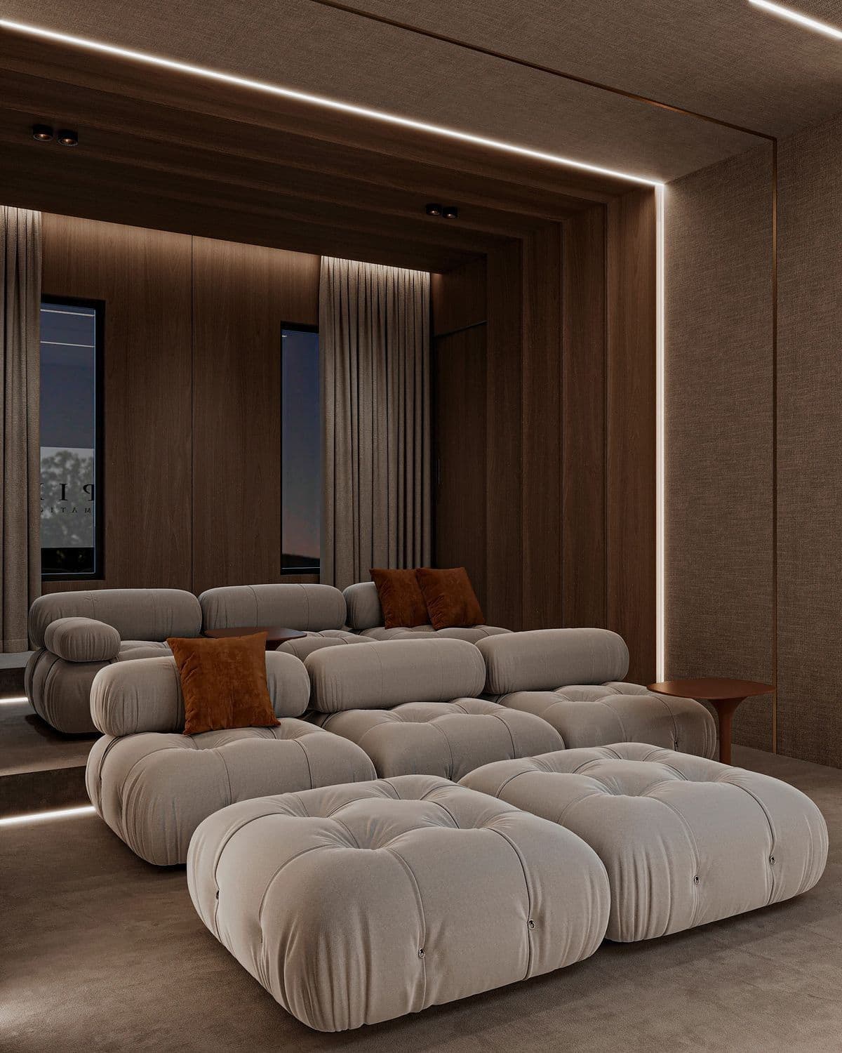A modular tufted sofa with a low profile, featuring rounded, voluminous cushions and cylindrical armrests. The sofa is upholstered in a textured, light-colored fabric and includes several loose cushions and an ottoman. A single brown accent pillow is visible on one of the seat cushions. — 3D model