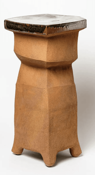An octagonal pedestal table featuring a faceted, unglazed ceramic body in an earthy brown tone, topped with a smooth, glazed surface displaying a marbling pattern of white, brown, and green hues. The body has a roughly textured, almost Brutalist appearance, with its geometric angles creating a sculptural form. The base of the pedestal flares out slightly to form four integrated feet. The glazed top exhibits characteristic drips and variations where it meets the unglazed body. — 3D model