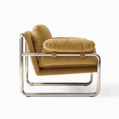 A modern armchair with a tubular chrome-plated steel frame and upholstered cushions. The frame forms a continuous loop supporting the seat, back, and armrests. The cushions appear to be filled with down or similar soft material, covered in a tan-colored fabric. — 3D model
