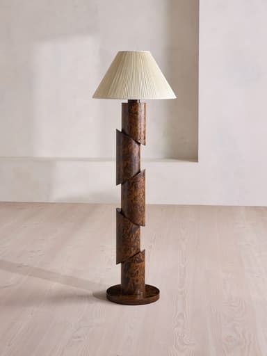 A tall floor lamp featuring a distinctive segmented and slightly spiraled stem made from burled wood or wood veneer, resting on a circular base. It is topped with a conical, pleated fabric lampshade in a light, neutral color. — 3D model