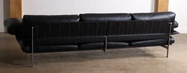 A modern three-seater sofa upholstered in black leather, featuring a minimalist design with a visible slim metal frame. It has three individual seat cushions, three back cushions, and detached, cushioned armrests, all in matching black leather. The sofa stands on slender metal legs, contributing to its sleek, elevated profile. — 3D model