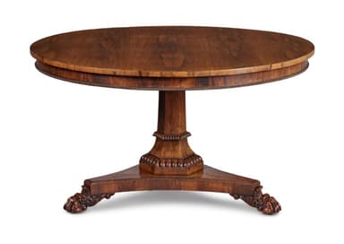 A round, wooden pedestal table with a rich, medium-brown finish. The tabletop features a finely reeded edge. It is supported by a central fluted column that rests on a tripartite base, with each splayed leg terminating in a carved paw foot. The base also features decorative carved detailing. — 3D model