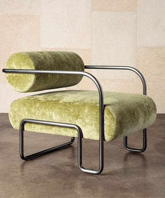 A contemporary armchair featuring a plush, cylindrical backrest and seat upholstered in a textured, olive-green velvet fabric. The armchair is supported by a minimalist, dark metal frame with curved legs and armrests. The design combines soft, rounded forms with a linear, industrial-inspired base. — 3D model