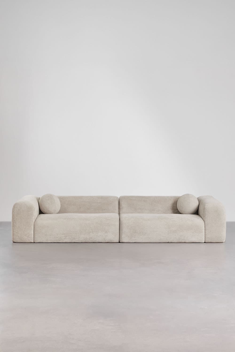 A two-piece modular sofa upholstered in a light beige boucle fabric, featuring a low-slung profile, deep seating, and softly rounded edges, accompanied by two spherical accent cushions. — 3D model