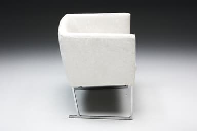 A set of four identical armchairs with a modern design. Each armchair features a cube-like upholstered seat and backrest with squared arms. The upholstery appears to be a textured fabric. The chairs are supported by a sleek, minimalist frame, likely made of polished metal, elevating them slightly off the ground. The overall aesthetic suggests a contemporary or minimalist style. — 3D model
