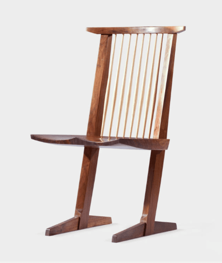 A wooden chair with a distinctive silhouette, featuring a sculpted seat, a high, angled backrest composed of vertical wooden slats, and splayed, angled legs that terminate in flat feet. The design exhibits a modern or mid-century aesthetic. — 3D model