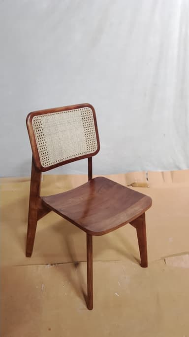 An armless side chair featuring a solid wood frame with a contoured wooden seat and a backrest incorporating a natural cane webbing insert, all in a warm brown finish. — 3D model