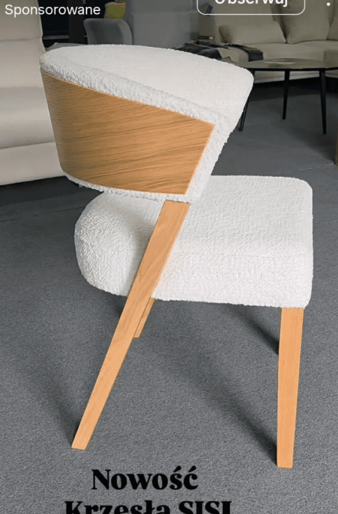 An upright dining chair featuring a curved backrest and integrated armrests, upholstered in white boucle fabric. The back of the chair has a prominent exposed light-toned wooden shell that forms the exterior of the curve and extends down to become the rear legs. The seat is also upholstered in the same white boucle fabric. Four tapered, cylindrical legs, matching the exposed wood of the back, support the chair. — 3D model